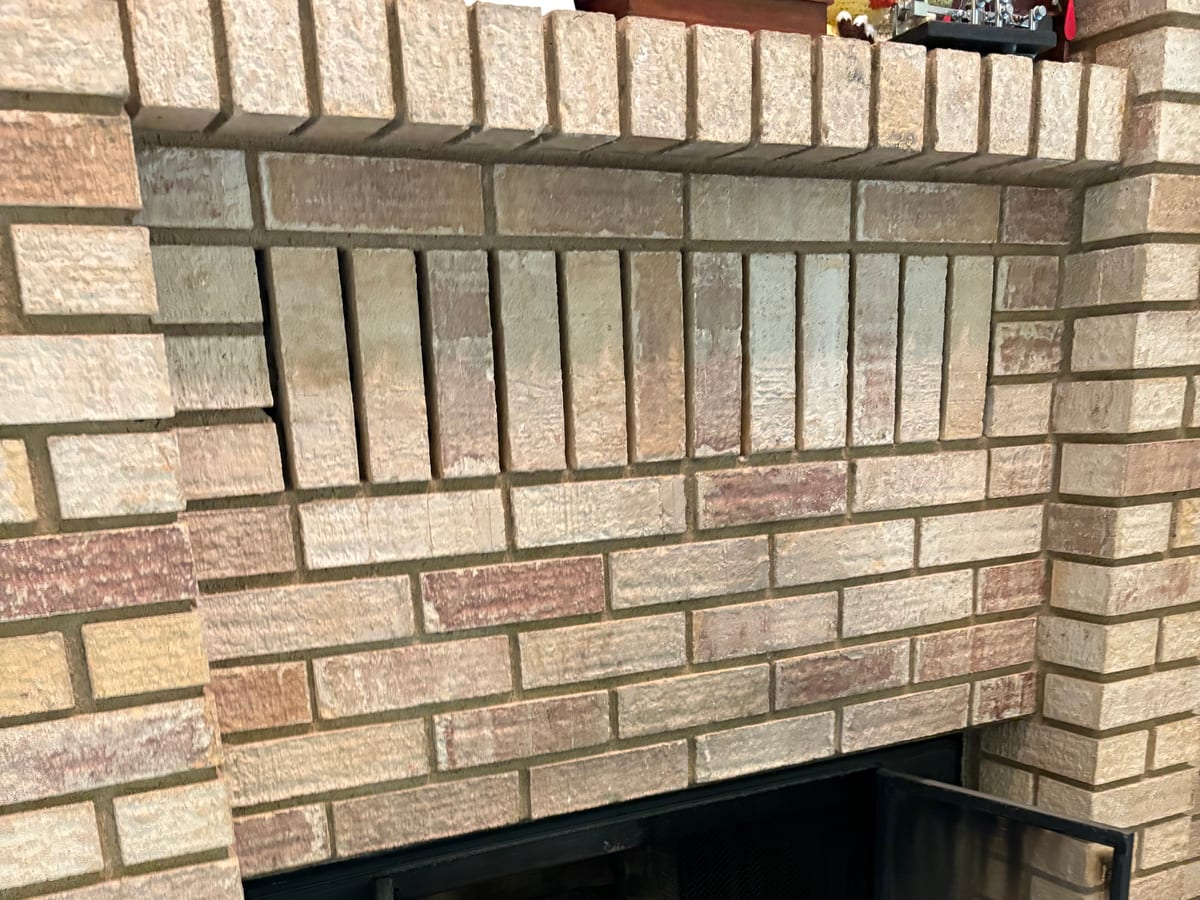 A brick fireplace with glass doors serviced by XFire Solution